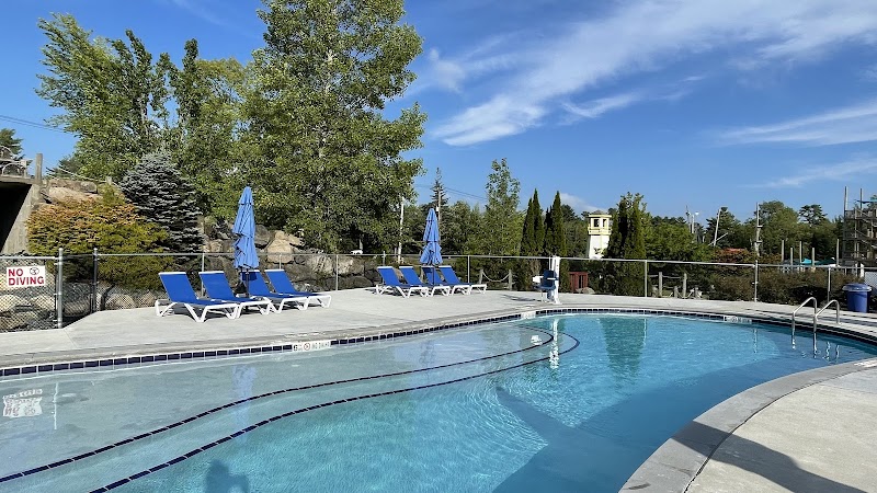 Pool area with blue lounge chairs and umbrellas at a campground in Acadia National Park on a sunny day.