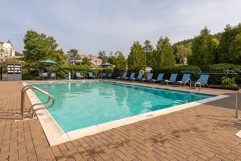 Hotel pool area in Acadia National Park with lounge chairs and trees surrounding the water