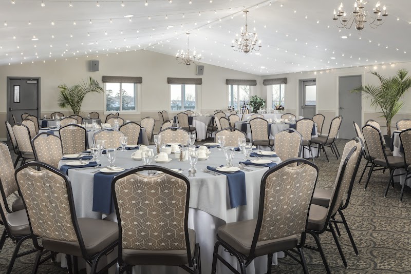 Banquet hall interior at an Acadia National Park lodging venue with round tables, white linens, and chandeliers under string lights.