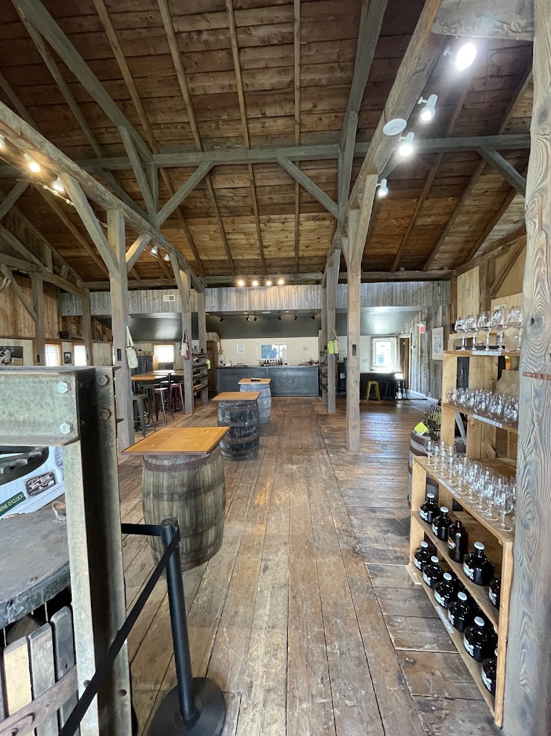 Interior of a rustic gift shop in Acadia National Park, featuring exposed wooden beams, barrels, and shelves of glassware.