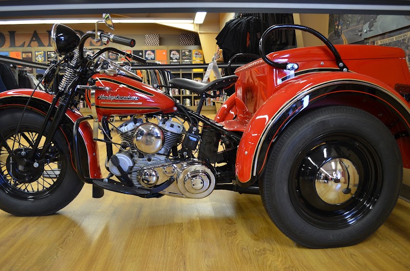 Vintage red Harley-Davidson motorcycle with a matching sidecar displayed on a wooden showroom floor at Badlands National Park gift shop.