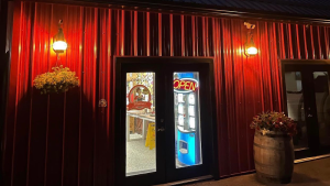 Night view of a restaurant entrance along a red metal wall in Acadia National Park, with OPEN sign and potted plants.