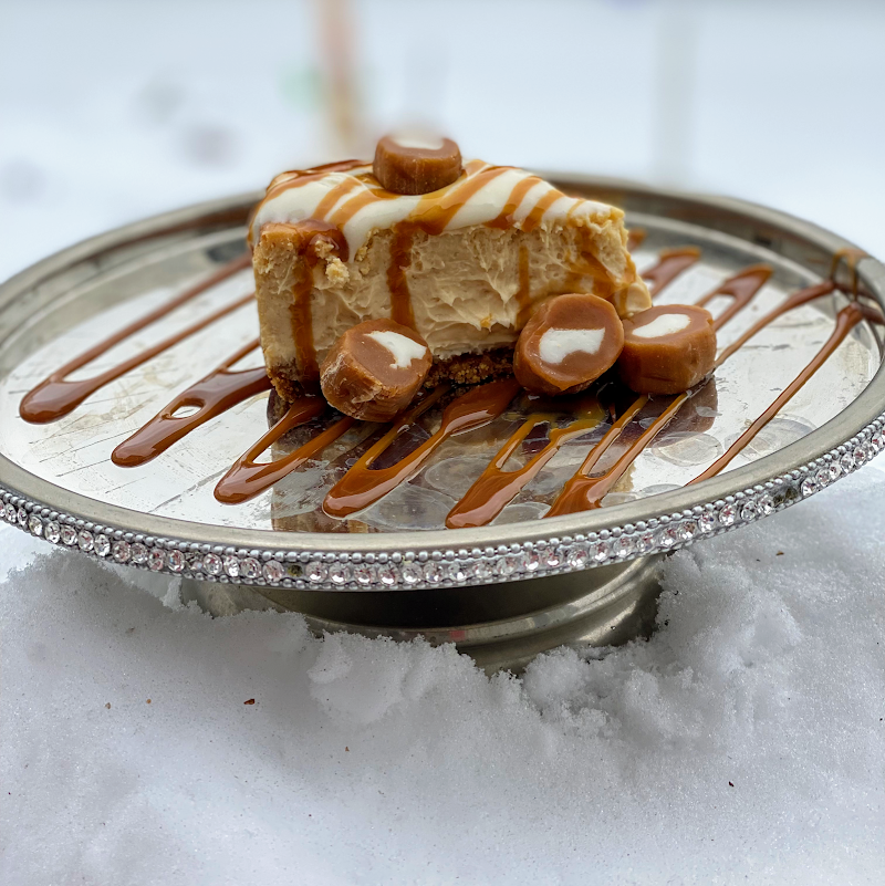 Creamy caramel-drizzled cheesecake served on a silver plate at Momo's Cheesecakes in Acadia National Park.