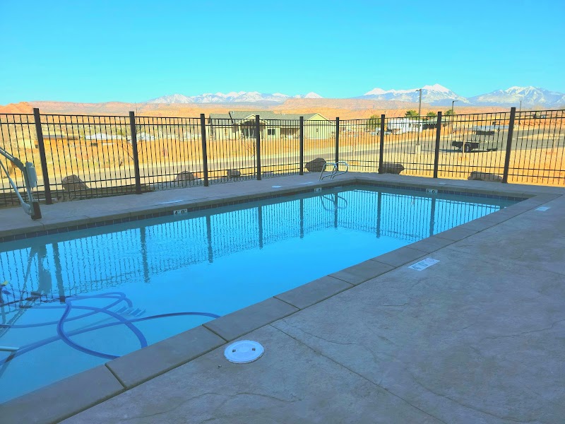 Pool area at a Moab lodging with desert landscape and distant mountains beyond a fenced patio in Arches National Park.