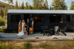 Wedding couple stands on the wooden steps of The Cabins at Blacktail in Glacier National Park, a rustic lodging setting.