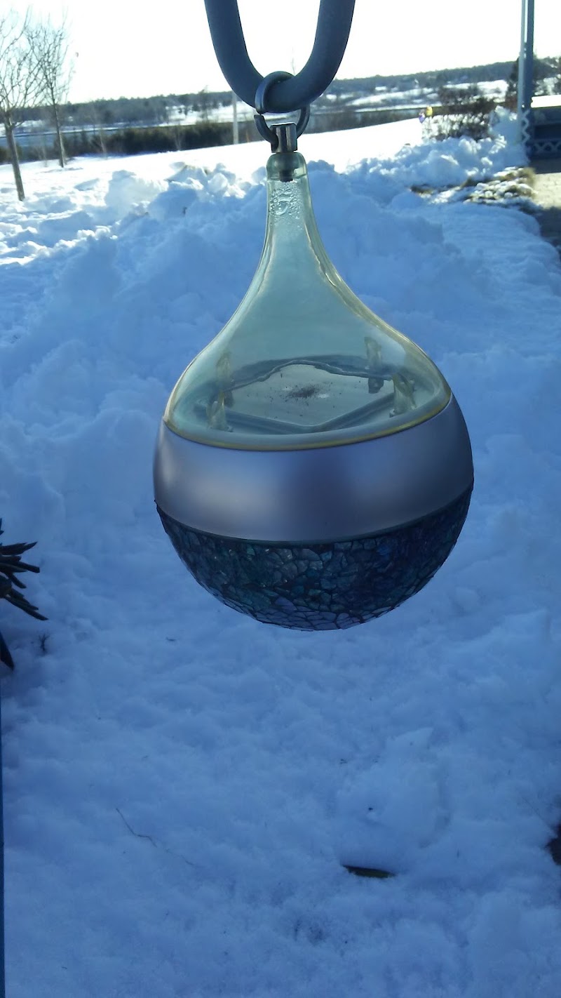 Lamoine in Acadia National Park shows a decorative glass pendant hanging outdoors amid fresh snow near a scenic coastal area.