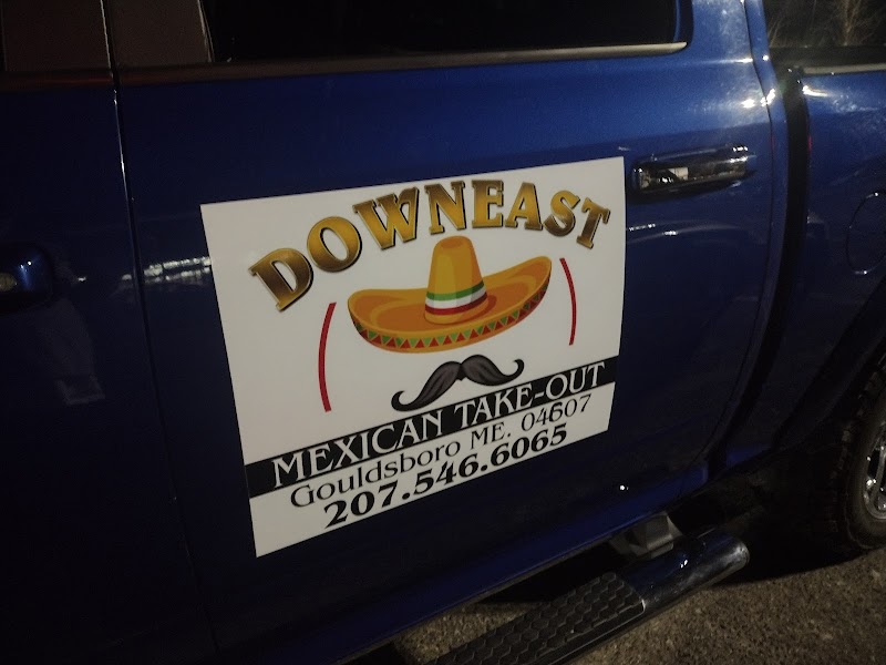 Blue pickup truck with a large white sign advertising Mexican takeout sits parked near Acadia National Park, featuring a sombrero graphic and mustache.