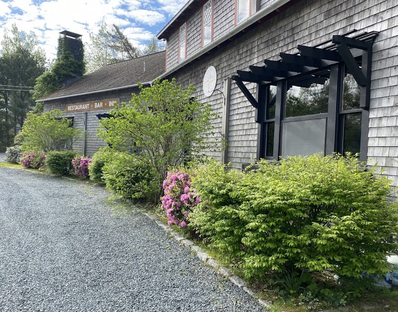 Exterior view of a wood-shingle restaurant and inn in Acadia National Park, framed by blooming shrubs.