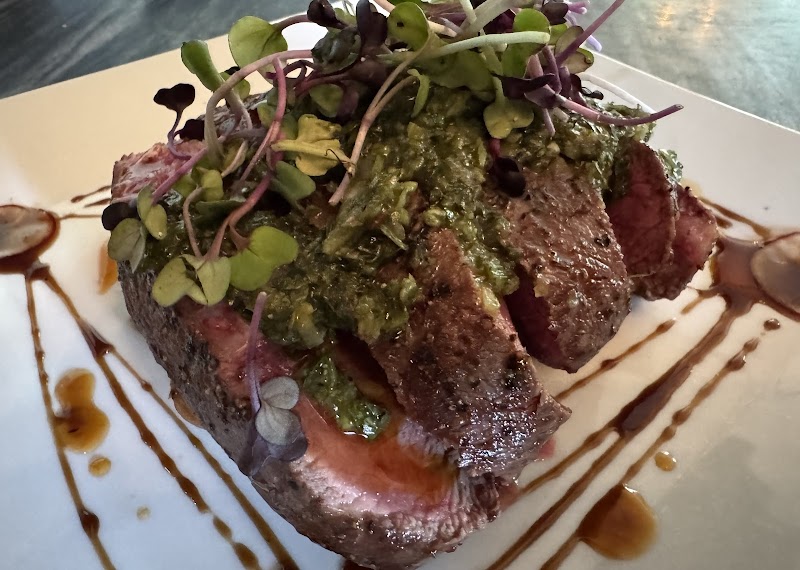 Sliced seared steak with herb greens plated at a dining venue in Acadia National Park.