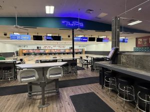 Indoor bowling alley eatery at Arches National Park featuring lanes, bar seating, high tables, and neon signage.