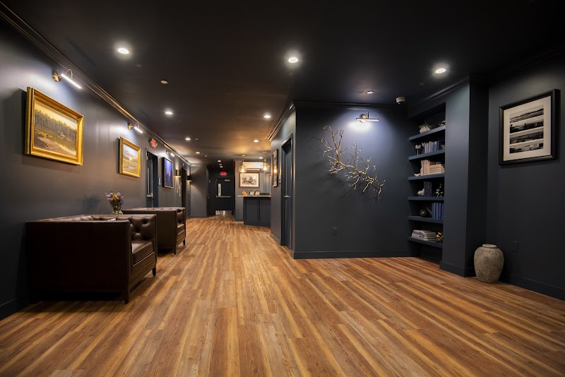 Lodge hallway in Acadia National Park with dark blue walls, leather seating, framed art, and a warm wood floor.