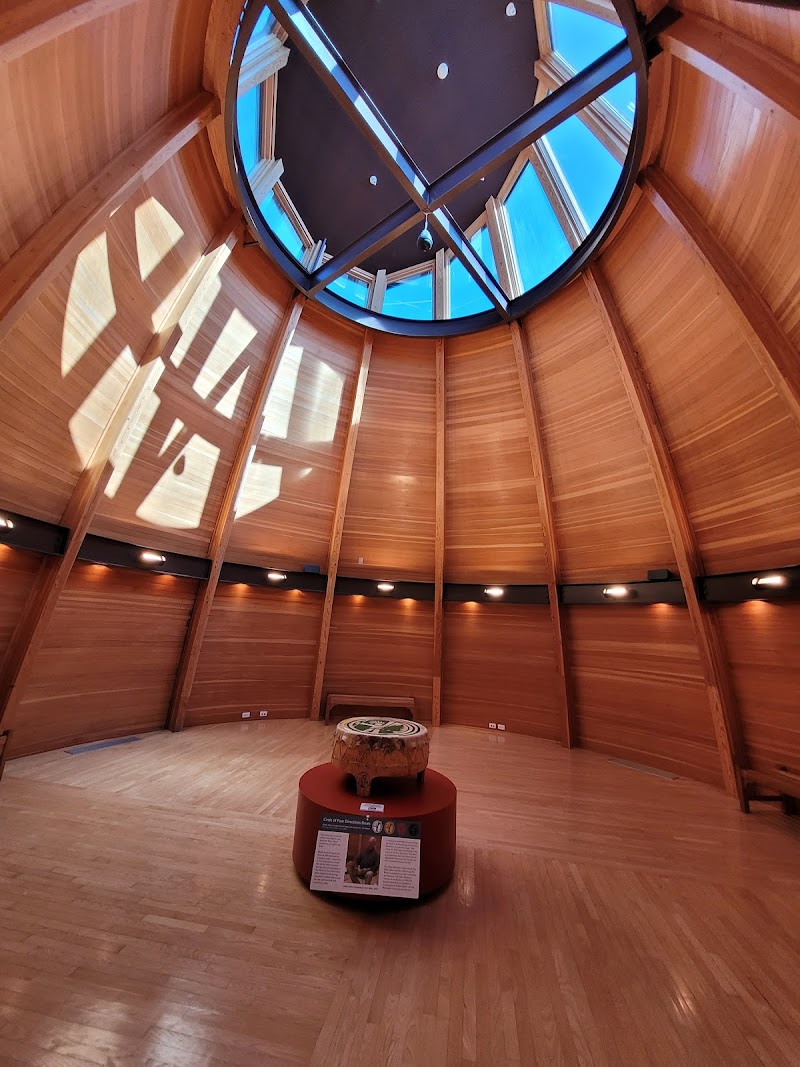 Circular cedar interior of a visitor center with a glass skylight dome overhead and sunlit wood panels in Acadia National Park.