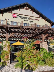 Exterior of a lodge-style hotel building with a wooden pergola and yellow umbrellas in Yellowstone National Park.