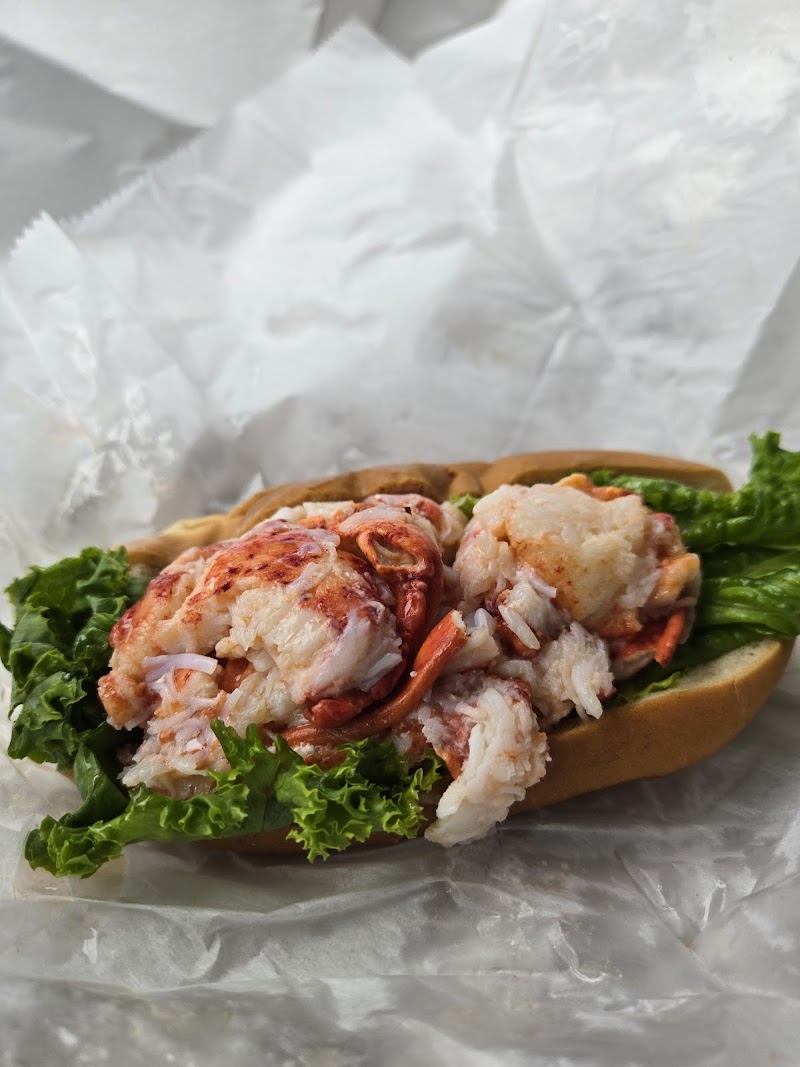 Lobster roll piled with tender lobster meat and crisp greens in a toasted bun, resting on white paper in Acadia National Park.