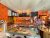 Bright orange ice cream shop interior in Acadia National Park, with a glass freezer and staff at the counter.