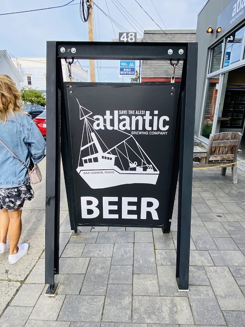 Black framed sidewalk sign with a white boat graphic and the word BEER, near a storefront in Acadia National Park.