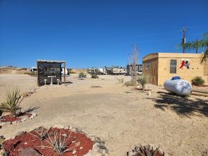 Desert campground at Big Bend National Park with RVs, a beige utility building, and sparse landscaping under a clear blue sky.