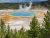 Fairy Falls area in Yellowstone National Park featuring the vibrant Grand Prismatic Spring nearby and steam rising from the hot springs.
