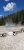 Sour Lake geothermal pool at Yellowstone National Park, steam rising from a blue pool surrounded by pine trees and a wooden barrier.