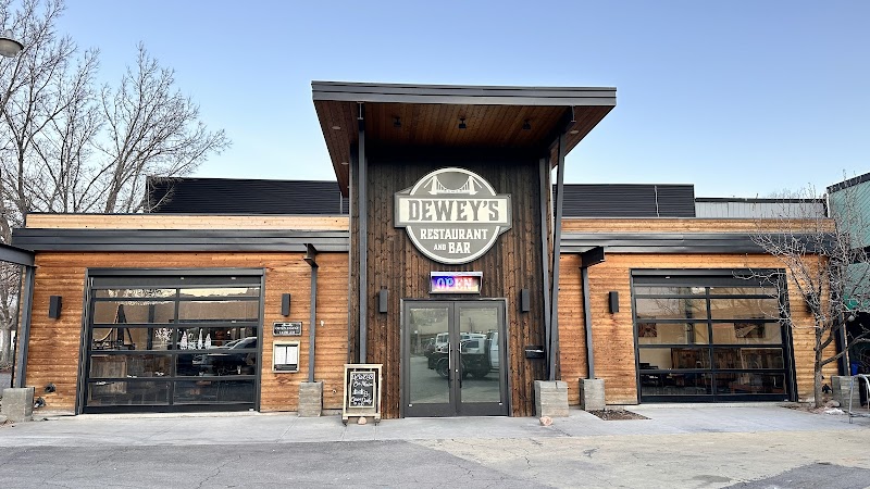 Wooden façade restaurant with large glass garage doors, a central entry and sign above, parking in Arches National Park.