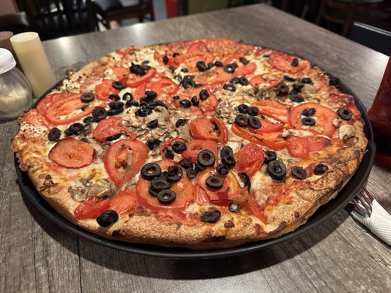 Pizza topped with tomatoes and black olives sits on a table at a Bucksport restaurant in Acadia National Park.
