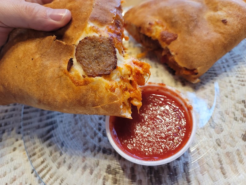Cheesy sausage sandwich with marinara sauce in a takeout cup, enjoyed near Acadia National Park.