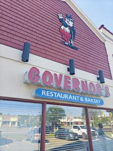 Exterior view of a storefront in Acadia National Park area, featuring a red-tiled facade and a cartoon character sign.