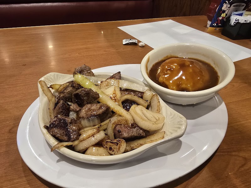 Steak tips with onions and potato wedges served with gravy in a dining setting at Acadia National Park.