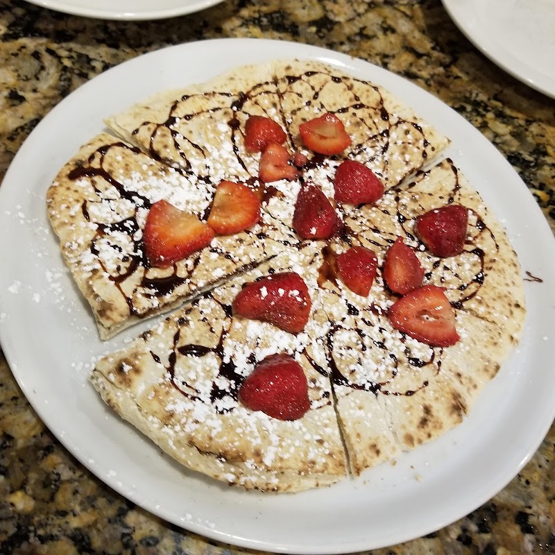 Flatbread dessert topped with strawberry pieces, powdered sugar, and a chocolate drizzle, plated at Arches National Park.