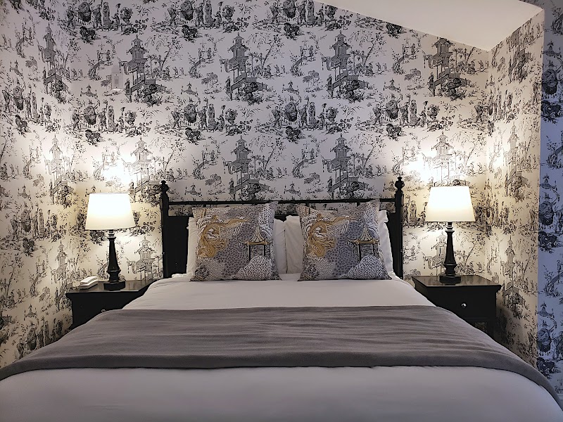Cozy bedroom featuring a black wrought-iron bed, twin nightstands with lamps, and toile wallpaper in Acadia National Park.