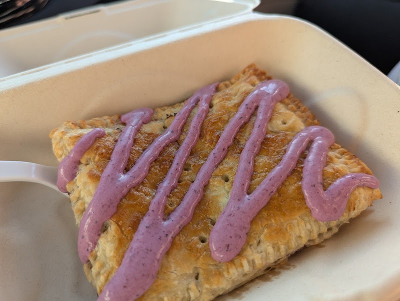 Glacier National Park pastry with purple icing served in a takeout container, enjoyed at a park cafe.
