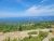 Rocky overlook at Acadia National Park with evergreen shrubs, green hills, and a blue Atlantic dotted by small islands.