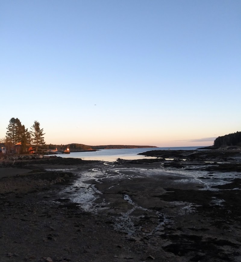Winter Harbor shoreline at Acadia National Park captures a tranquil Atlantic sunset along rocky shores.