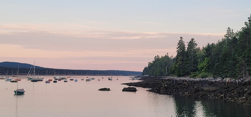 Winter Harbor, Acadia National Park, Maine, boats anchored along a rocky shoreline at sunset with calm water.