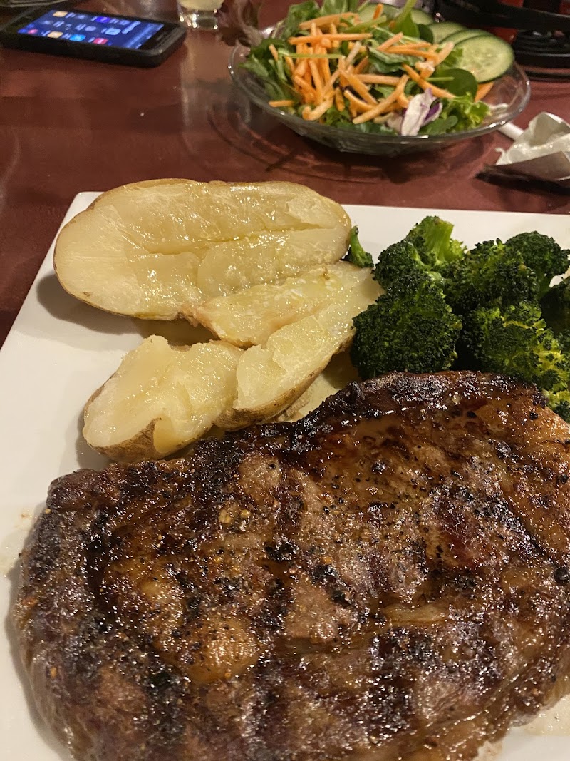 Juicy grilled steak with roasted potatoes and broccoli, plus a side salad in the background, Yellowstone National Park.