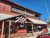 Red wooden restaurant exterior with a slanted gray awning, outdoor seating, and a Welcome sign in Arches National Park.