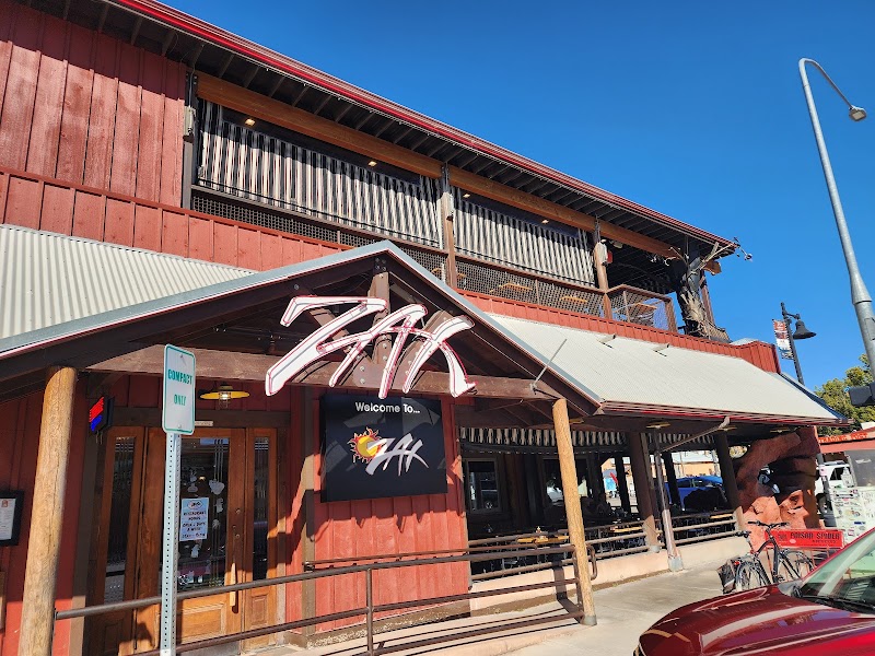 Red wooden restaurant exterior with a slanted gray awning, outdoor seating, and a Welcome sign in Arches National Park.