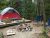 Camping setup at Quietside Campground in Acadia National Park, with a red tent on a wooden platform, campfire ring, and blue chairs nearby.
