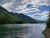 Shoreline at Harrison Lake near Glacier National Park, with forested mountains and a calm, reflective surface.