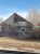 Weathered wooden cottage with boarded windows and weathered siding sits in a barren yard at Badlands National Park.