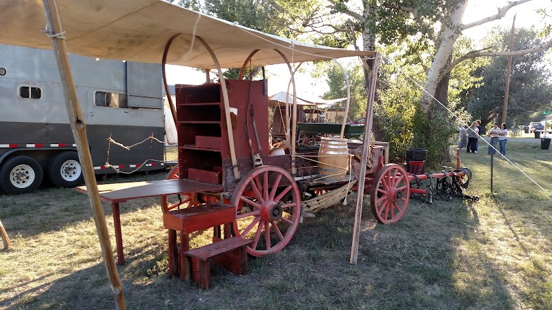 Vintage wooden wagon with red wheels, shelves, and barrels under a canvas canopy at Badlands National Park.