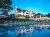 Poolside view of a white lodge with umbrellas and lounge chairs at Acadia National Park, reflecting in a calm pool.