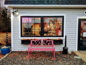 Pastel pink bench sits outside a small cafe storefront in Acadia National Park during autumn.