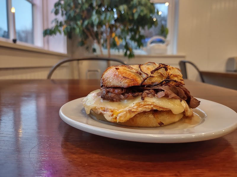Cozy cafe interior at Acadia National Park with a toasted breakfast sandwich on a white plate under warm lighting.
