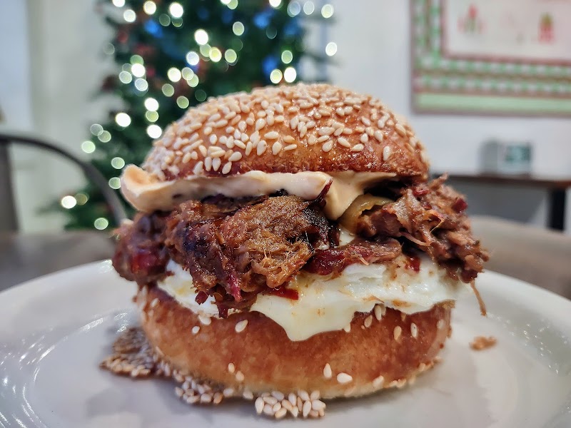 Beef sandwich with melted cheese and pulled meat on a sesame bun, served in a cafe setting in Acadia National Park.