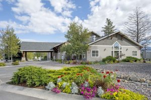 Lodge exterior near Glacier National Park with a landscaped flower bed and a paved driveway.