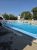 Outdoor pool at Hadley's Point Campground in Acadia National Park, with swimmers, a white fence, and blue sky.