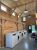 Warm wood-clad laundry room with a row of front-loading washers, exposed beams, and hanging lights in Acadia National Park campground.