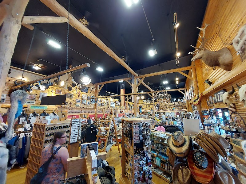 Busy gift shop inside a wooden lodge at Badlands National Park, with ceiling beams, hanging lights, shelves of hats and souvenirs, and mounted animal heads.