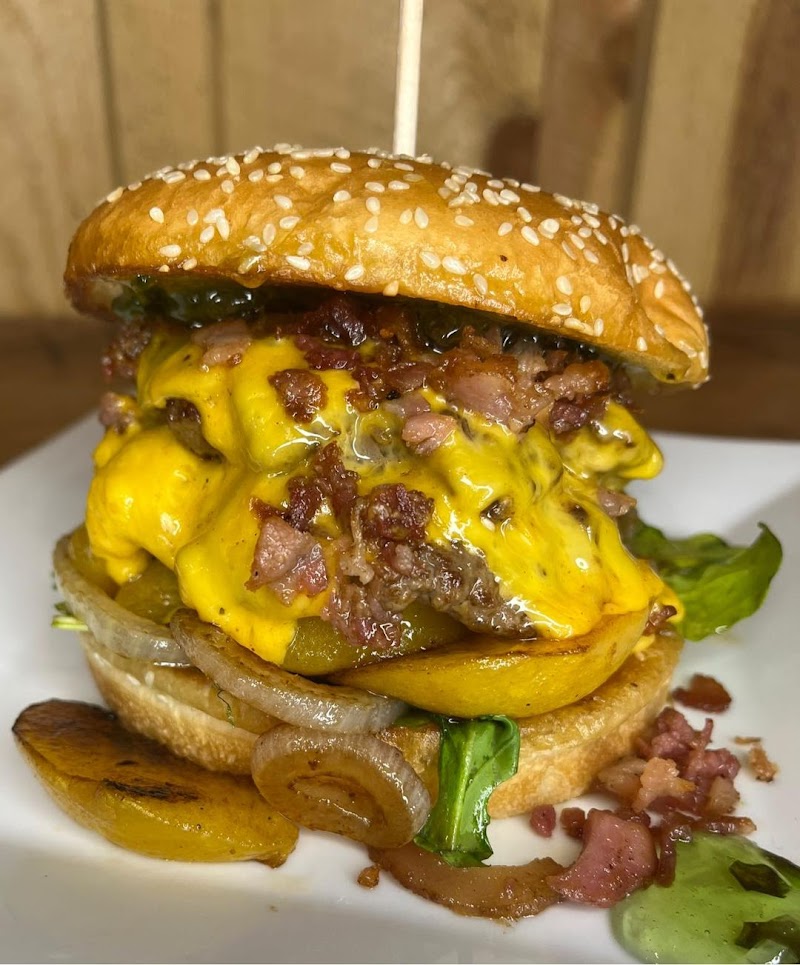 Overstuffed cheeseburger with melted cheddar, bacon, onions, pickles and lettuce on a sesame bun with potato wedges in Badlands National Park.